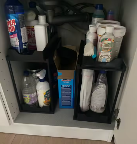 Two organisers installed under a sink, one for the kitchen and one for the bathroom